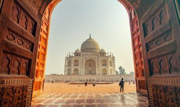 Introduction The Taj Mahal, standing gracefully on the banks of the Yamuna River in Agra, Uttar Pradesh, is more than just an architectural marvel. Declared a UNESCO World Heritage Site in 1983, it represents the pinnacle of Mughal architecture, blending Persian, Islamic, and Indian styles. Globally recognized as a symbol of eternal love, the Taj Mahal continues to captivate millions of visitors each year with its exquisite beauty and poignant history. Historical and Cultural Background Commissioned in 1632 by the Mughal Emperor Shah Jahan, the Taj Mahal was built in memory of his beloved wife Mumtaz Mahal, who died during childbirth. It took approximately 22 years and more than 20,000 artisans, architects, and laborers to complete. The structure is made primarily of white Makrana marble and inlaid with semi-precious stones, symbolizing both material opulence and emotional depth. The cultural significance of the Taj Mahal lies in its representation of Mughal artistic sensibilities during the empire’s golden age. It reflects the fusion of diverse traditions—Persian charbagh gardens, Islamic calligraphy, and Indian floral motifs—into a harmonious expression of both power and devotion. Architectural Uniqueness The Taj Mahal’s design is a masterclass in symmetry and harmony. The central dome, flanked by four smaller domes and minarets, creates an ethereal skyline. The structure appears to change color depending on the time of day—soft pink at dawn, bright white at noon, and golden at dusk—symbolizing the changing moods of love. Other unique features include: The Calligraphy: Verses from the Quran are inscribed in elegant Thuluth script. The Gardens: The charbagh (four-part) garden represents the Islamic concept of paradise. The Reflecting Pool: It mirrors the Taj, adding to its illusion of floating beauty. Value to Humanity As a UNESCO World Heritage site, the Taj Mahal is recognized for its outstanding universal value. It serves as a cultural touchstone for millions, offering a shared symbol of devotion that transcends religion, language, and geography. Its architectural brilliance continues to inspire artists, poets, and architects around the globe. The Taj Mahal is also a crucial part of India’s identity and heritage, often regarded as the crown jewel of the country’s historical monuments. It embodies not just artistic and architectural excellence, but also emotional and philosophical depth. Transformational Experience Visiting the Taj Mahal can be a profoundly moving experience. The serenity of the location, the craftsmanship of the structure, and the poignant love story behind its construction evoke introspection. Many visitors report a heightened appreciation for human creativity, love, and the impermanence of life. This transformational journey encourages reflection on one’s own relationships and priorities, drawing a parallel between the timeless monument and the transient nature of our own lives. Social and Cultural Impacts Tourism and Economy: The Taj Mahal contributes significantly to India’s tourism industry, creating jobs and supporting local businesses. Cultural Diplomacy: It often serves as a backdrop for international diplomacy and cultural exchange. Symbol of India: Like the Eiffel Tower for France or the Statue of Liberty for the U.S., the Taj Mahal is a globally recognized emblem of Indian heritage. Rationale Behind Its Popularity The Taj Mahal’s enduring popularity can be attributed to: Its emotional backstory rooted in love and loss. Architectural symmetry and beauty. International recognition as one of the Seven Wonders of the Modern World. Its accessibility and romantic appeal, making it a favorite destination for both Indian and foreign travelers. Comparisons with Other World Monuments Monument Similarity Unique Feature Eiffel Tower, France Romantic symbol Modern industrial design Petra, Jordan UNESCO Heritage site Rock-cut architecture Machu Picchu, Peru Historic significance Altitude and landscape Pyramids of Giza, Egypt Royal tombs Ancient engineering Colosseum, Italy Architectural grandeur Entertainment legacy While each monument has its charm, the Taj Mahal stands apart for being an emotive fusion of art, architecture, and eternal love. Lessons from the Taj Mahal Love Endures: Even centuries later, Shah Jahan’s love story continues to touch lives. Craftsmanship Matters: Human creativity can produce timeless beauty. Impermanence and Legacy: Life is fleeting, but what we create in love can become immortal. Harmony Through Diversity: The blending of artistic styles shows how cultural integration leads to beauty. Conclusion The Taj Mahal is not just a monument—it is a message carved in marble, echoing through the ages. It reminds us of love’s timeless power, of the beauty of human craftsmanship, and of the enduring cultural richness of India. A visit to this ethereal palace is more than a touristic journey—it is a soulful pilgrimage into the essence of devotion, creativity, and history.